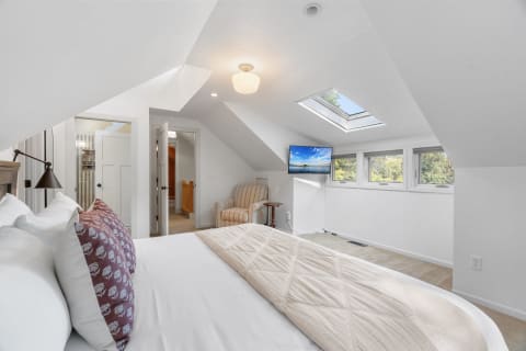 Bright and airy attic bedroom with sloped ceilings and a skylight.