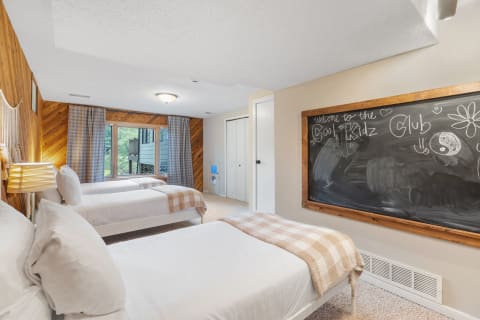 Children's bedroom with three beds and a chalkboard with playful drawings.