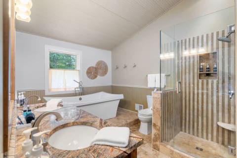 Spacious modern bathroom with freestanding bathtub, glass shower, and granite countertops.