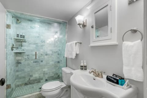 Stylish bathroom with a marble shower, white vanity, and elegant lighting.