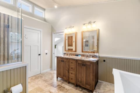 A beautifully designed bathroom featuring a wooden vanity, glass shower, and freestanding bathtub.