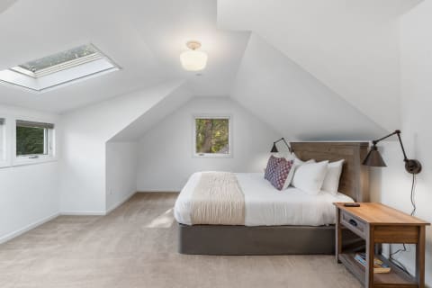 Bright attic bedroom with a large skylight and a queen-sized bed.