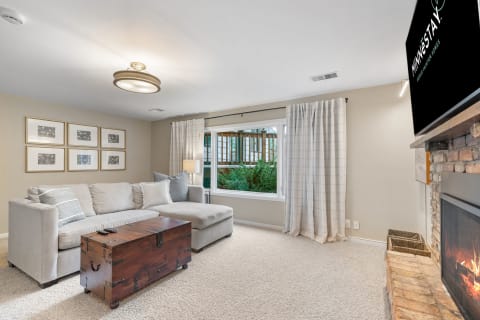 Cozy living room featuring a sectional sofa, wooden coffee table, and a stone fireplace with a television above.