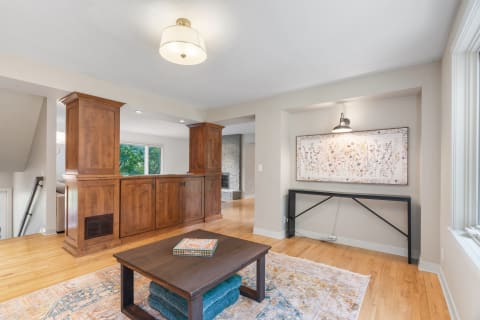 Cozy living room featuring a wooden coffee table, colorful rug, and floral artwork.