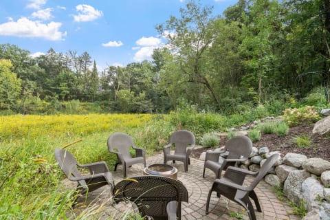 An outdoor seating area with chairs and a fire pit in a field of yellow flowers.