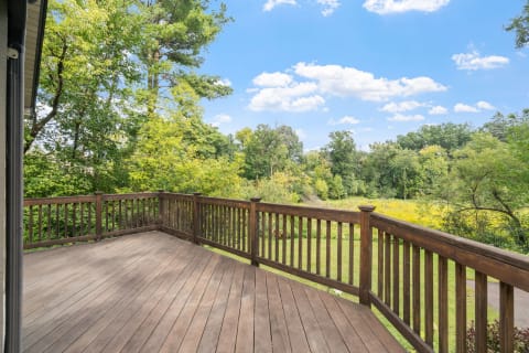 Wooden deck with a view of greenery and blue sky.