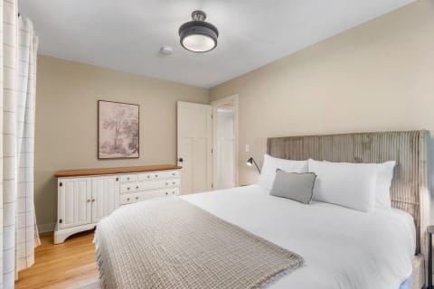 A cozy bedroom featuring a bed, dresser, and framed art on the wall.
