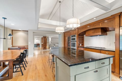 Modern kitchen with granite island, blue cabinetry, and wooden dining table.