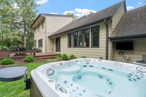 A contemporary house featuring a hot tub and a wooden deck in a tranquil outdoor setting.