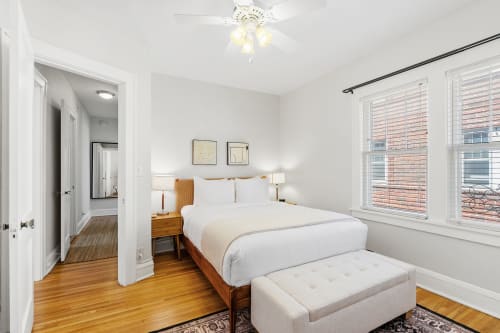 Sink into crisp white linens and warm wood tones in your peaceful retreat, where morning light streams through large windows.