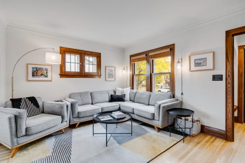 Sink into plush gray sectional seating where warm wood accents and natural light create your perfect retreat for morning coffee or evening relaxation.