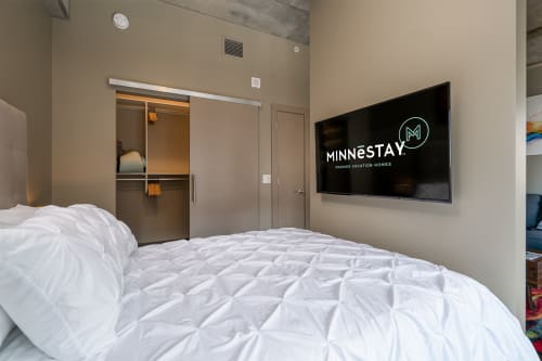 Sink into crisp white linens and unwind while watching your favorite shows on the large flat-screen TV in this modern bedroom.