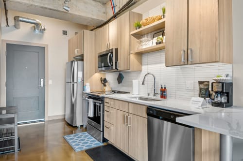 Step into your sleek modern kitchen with stainless steel appliances, warm wood cabinets, and everything needed for your stay.