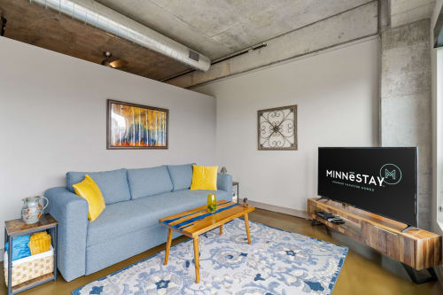 Unwind in your stylish loft living room with exposed concrete ceiling, cozy blue sectional, and modern industrial charm.