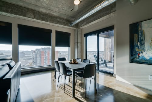 Gather around your sleek dining table with panoramic city views stretching beyond floor-to-ceiling windows, where industrial chic meets modern comfort.