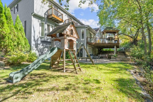 A tranquil backyard featuring a wooden play structure and modern home.