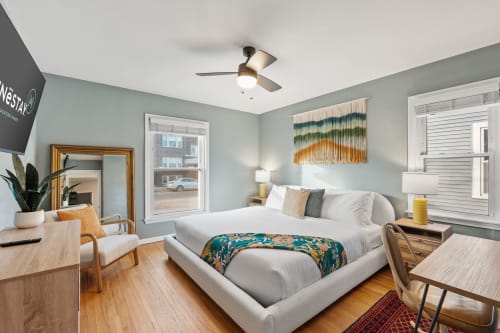 Unwind in your peaceful bedroom with soft linens, modern ceiling fan, and vibrant artwork creating the perfect retreat.