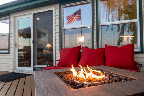 Cozy up around your private fire table as evening approaches, with plush red cushions and mountain views creating the perfect lakeside retreat.